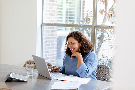 Small business owner meets virtually with a financial advisor - stock photo The small business owner smiles while attending a virtual meeting with her financial advisor to review upcoming changes to her taxes.