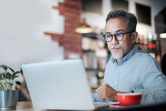 senior man having discussion with his colleague via online virtual meeting in a cafe - stock photo