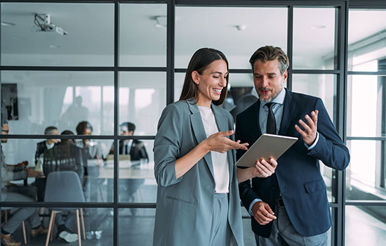 Business people in the office. - stock photo Shot of two coworkers having a discussion in modern office. Businessman and businesswoman in meeting using digital tablet and discussing business strategy. Confident business people working together in the office. Corporate business persons discussing new project and sharing ideas in the workplace.