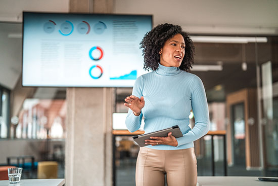 Portrait of a Woman Giving a Speech Using Technology - stock photo Front view portrait of a woman giving a speech. She has short curly hair as is holding a digital tablet in her hands.