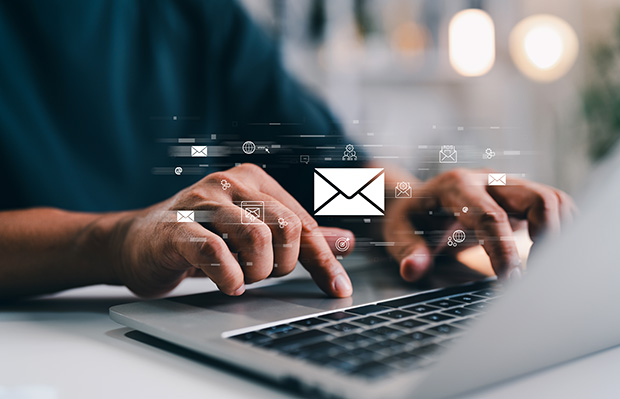 Hands of A Businessman using Laptop typing on keyboard computer and surfing internet on office table with email marketing and email icon. stock photo