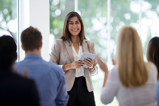 Clapping After a Presentation - stock photo A multi-ethnic group of business professionals are listening to a presentation from a colleague during a meeting in the boardroom. They are clapping after a presentation.