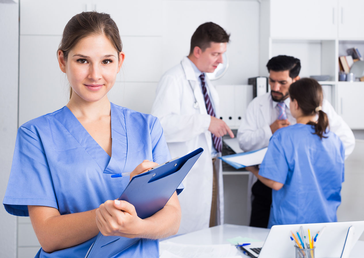 Smiling young female doctor writing notes on clipboard in clinic