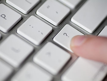 A person pressing the question mark key on a keyboard.