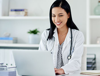 Picture of a young doctor using a laptop at her desk.