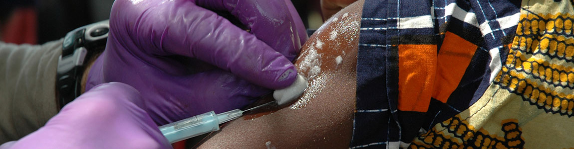 Vaccination - Needle - stock photo A doctor gives a life saving shot in the arm to an African in his village.