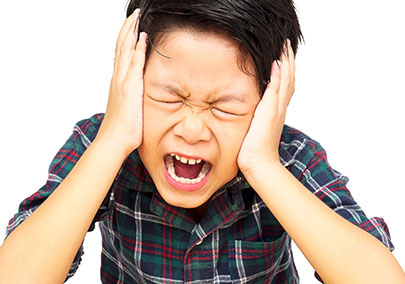 Portrait of preteen boy looks sad while having headache and standing in the studio, isolated on white background