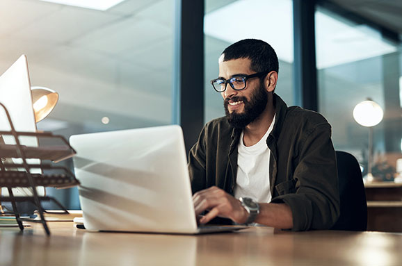 Shot of a young businessman using a laptop during a late night in a modern office