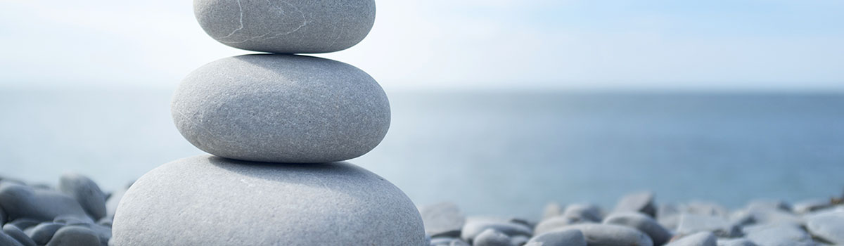 "A zen like pebble stack next to the sea. Ideal image for health, wellness and relaxation themes.